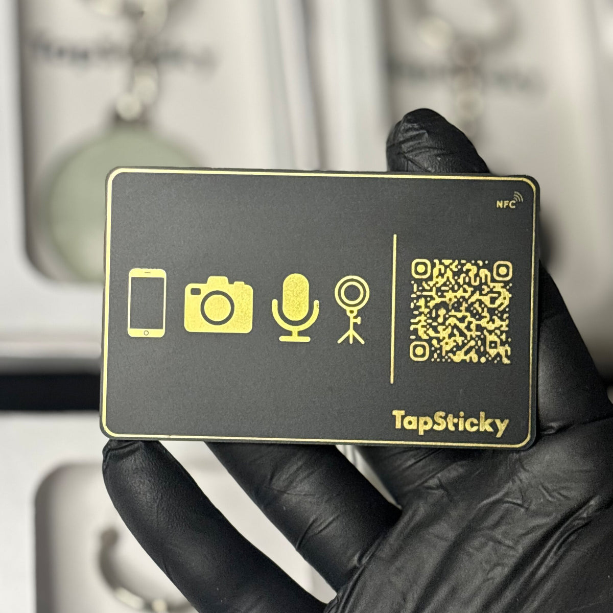 Real TapSticky black NFC card with gold foil, held in hand
