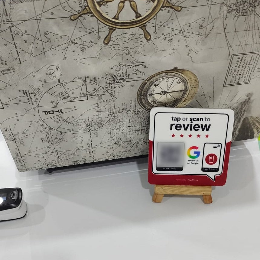 TapSticky review plate standing on a small wooden easel on a white clinic desk, in front of a laptop